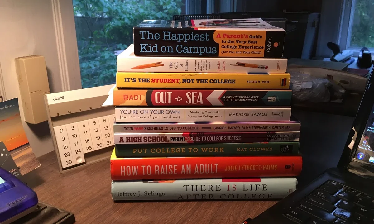 A stack of books sits on a desk with a June standup calendar sitting behind the stack